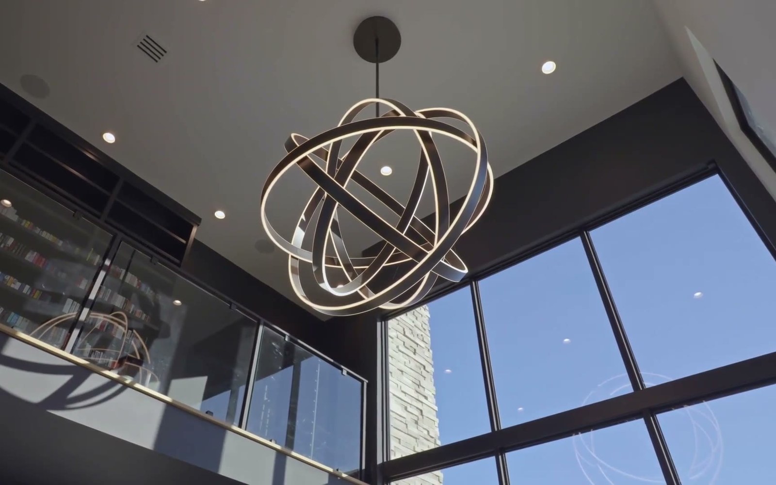 Lutron motorized shades half lowered over a wall of tall glass doors